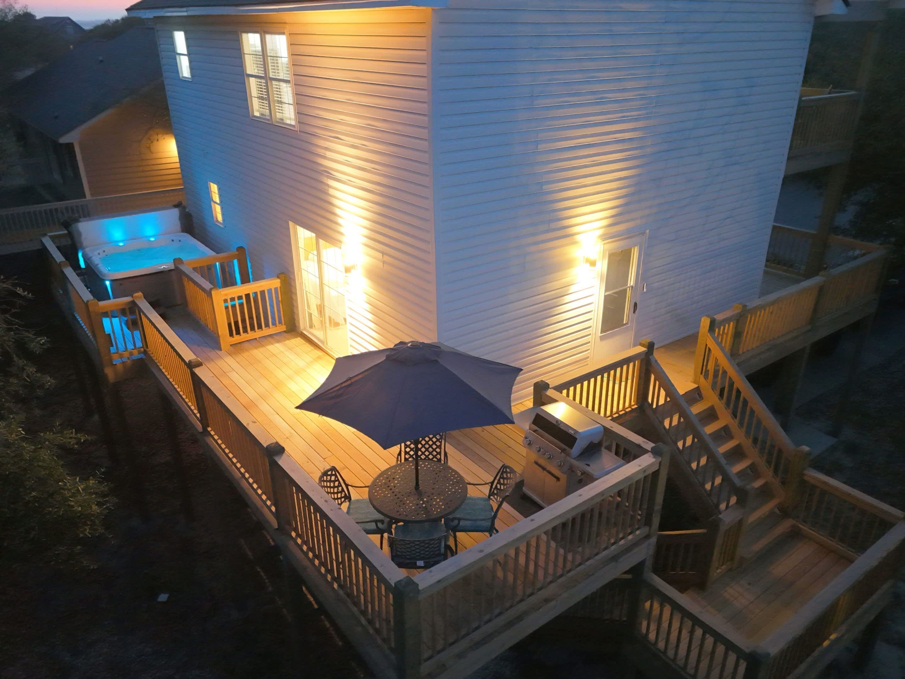 A two-story house with a deck, outdoor seating, and a hot tub.