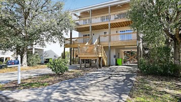 A multi-story residential building with a wooden deck and a covered outdoor area.
