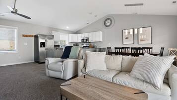A modern living room with a sofa, a coffee table, and a dining area with chairs.