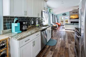 A modern kitchen with white cabinets, a coffee maker, and a dishwasher. - The Gulf House | Walk to Beach | 5BR Retreat (Treasure Island)