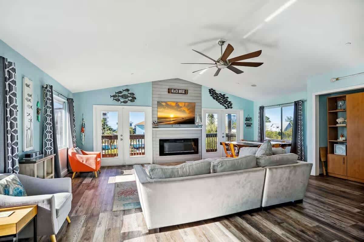 A living room with a fireplace, a ceiling fan, and a view of the outdoors.