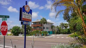 Straatbeeld met stopteken, bord voor Treasure Island Beach Access en een gebouw met balkon.