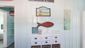 Eine Wand mit einem gerahmten Schild, einer Fischdekoration und einem Schild mit Strandbezug.