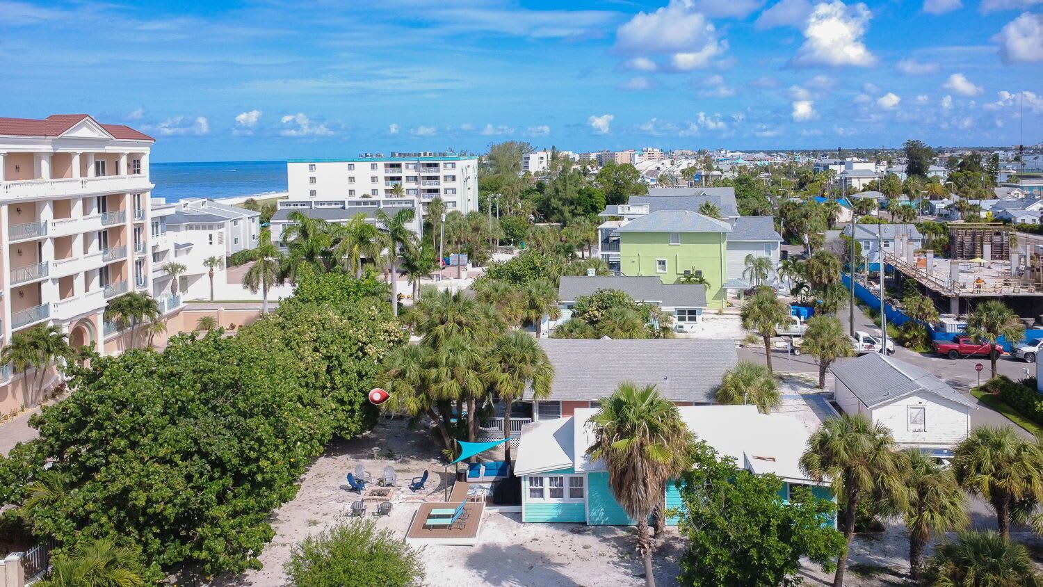 A coastal town with beachfront properties, including a hotel with multiple balconies and a pool area.