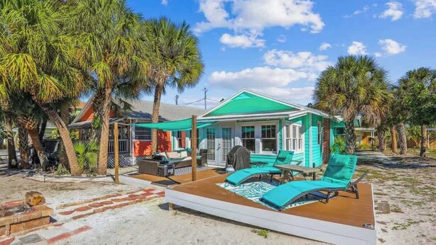 Ein Anwesen direkt am Strand mit überdachter Terrasse, Sitzgelegenheiten im Freien und einem Poolbereich.