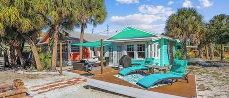 Una propiedad frente a la playa con un patio cubierto, mobiliario exterior y zona de piscina.