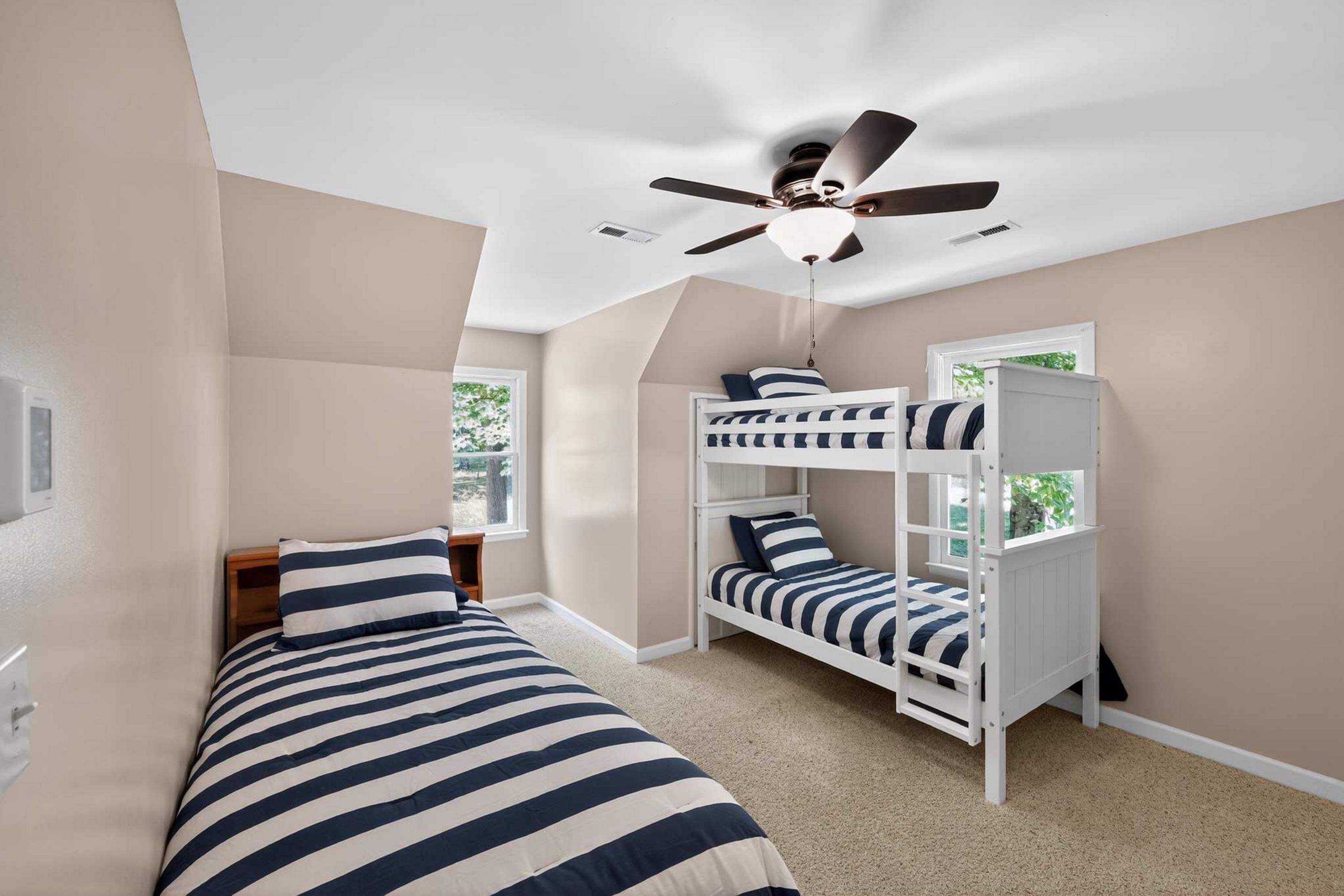 A room with bunk beds, a ceiling fan, and a window.