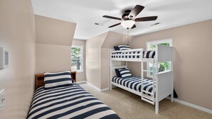 Ein Zimmer mit Etagenbetten, Deckenventilator und Fenster.