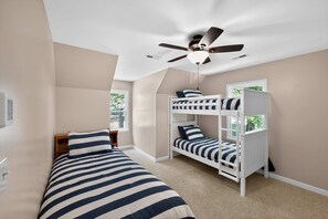 A room with bunk beds, a ceiling fan, and a window.