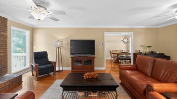 Una sala de estar con sofá, sillón, mesa de centro, televisor y un comedor con sillas y mesa.