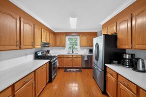 A kitchen with wooden cabinets, a stainless steel refrigerator, a stove, and a microwave. - Spacious 4 BR Retreat Near Lake Norman With Deck (Denver)