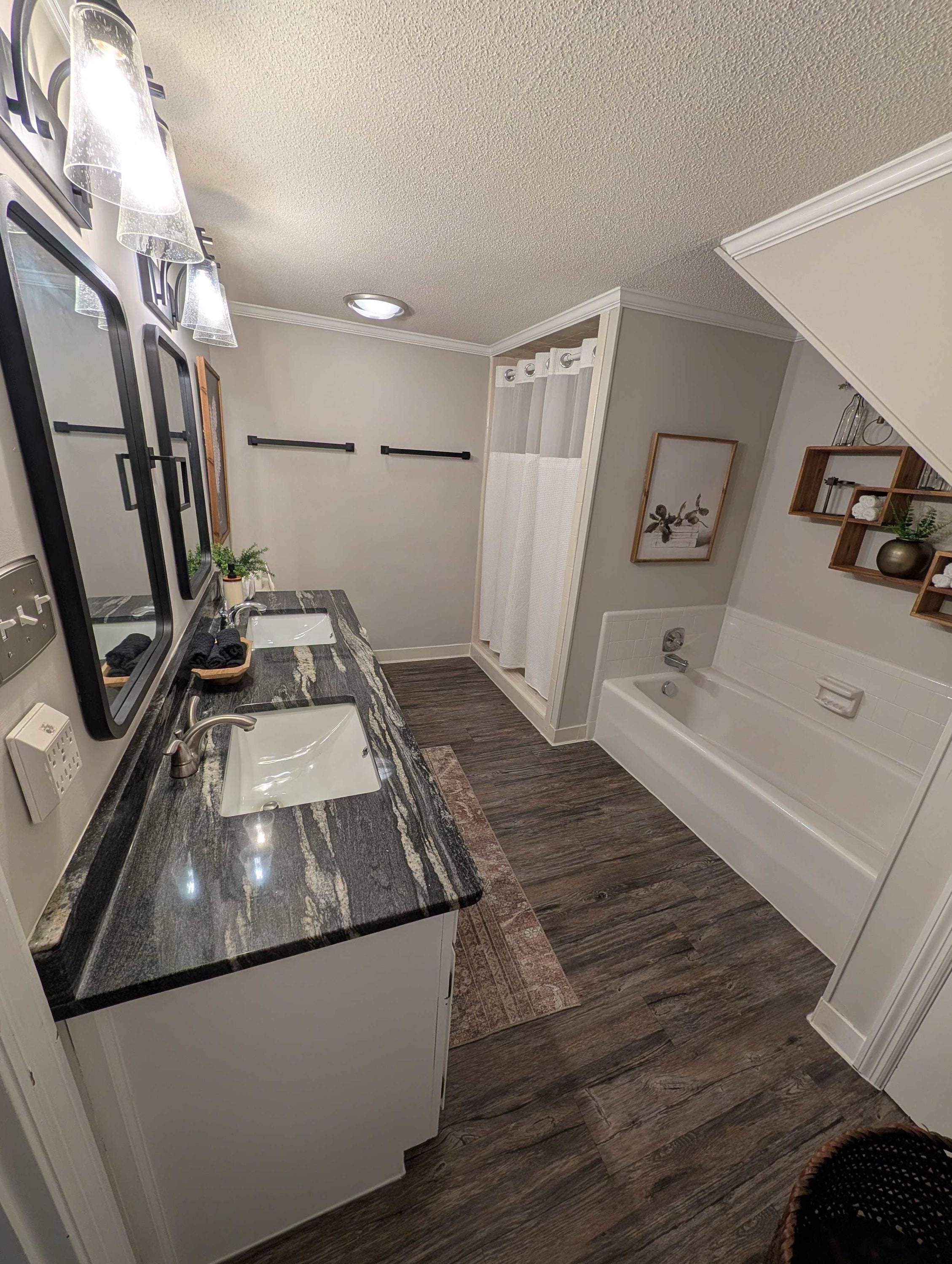 A modern bathroom with a marble sink, a bathtub, and a shower area.