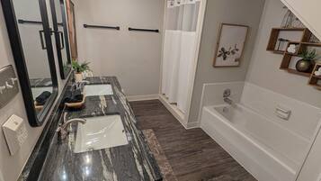 A modern bathroom with a marble sink, a bathtub, and a shower area.