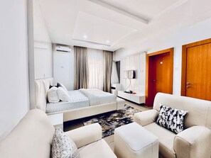 A modern hotel room with a bed, a sofa, a TV, and a wardrobe. - Luxury 5-Bedroom Apartment in Lekki 1 with Snooker, Fast Wi-Fi & 24/7 Power (Lagos)