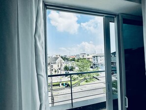 Une fenêtre donnant sur un quartier résidentiel, avec vue sur des maisons et une rue.
