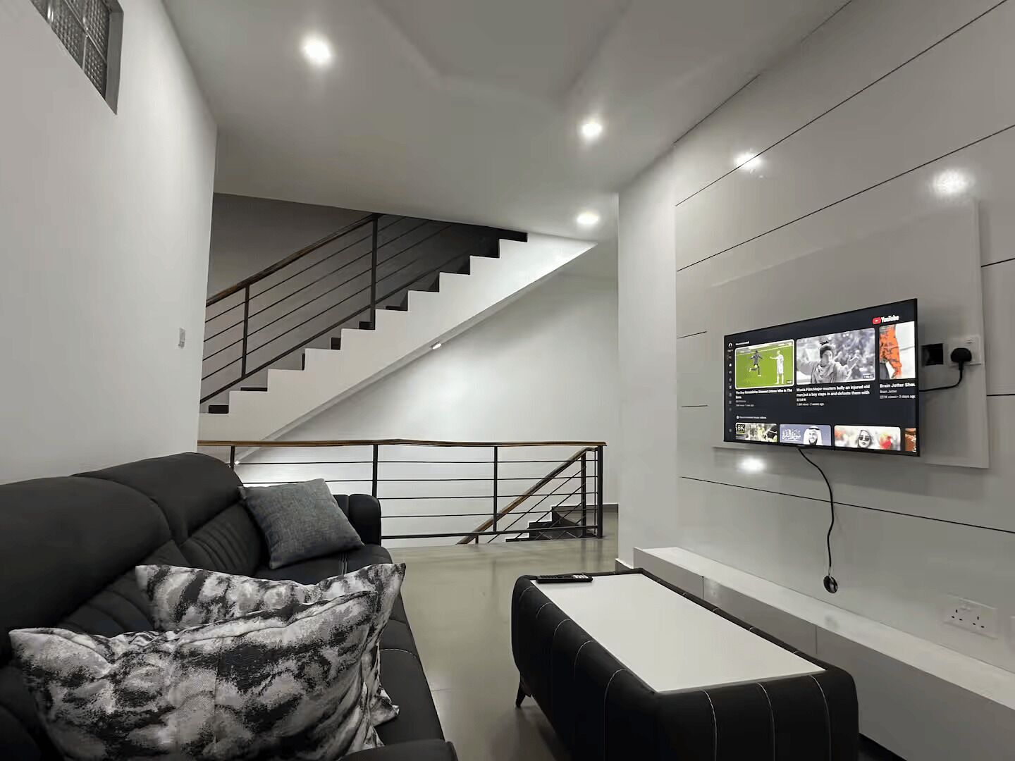 A modern living room with a sofa, a coffee table, and a TV mounted on the wall.