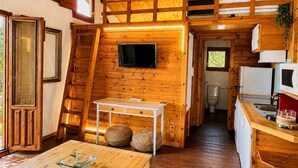 Interior acogedor de una cabaña con habitación en altillo, comedor y cocina.
