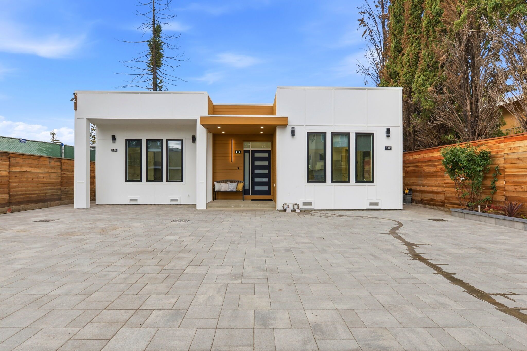 A modern two-story building with a central entrance, large windows, and a paved courtyard.