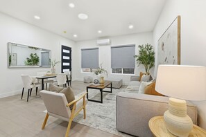 Una sala de estar moderna con un sofá, sillas, una mesa de centro y una lámpara.
