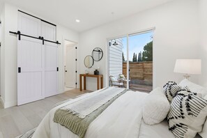 Un dormitorio con cama, mesita de noche, lámpara, ventana y puerta corredera.