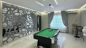 Una habitación moderna con mesa de billar, un muro decorativo y una zona de estar.