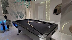 Una mesa de billar moderna con superficie de fieltro negro, rodeada por un suelo pulido.