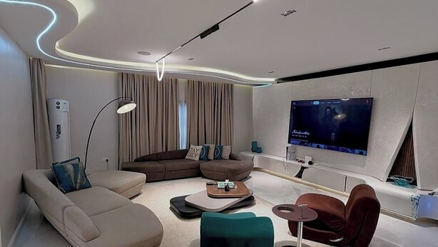 Una sala de estar moderna con un sofá modular, una mesa de centro, un televisor y una lámpara de pie.