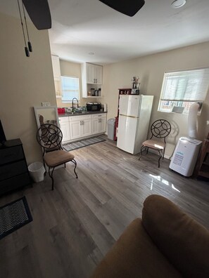 Un espacio habitable compacto con kitchenette, una zona de comedor con dos sillas y un sofá.