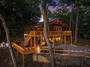 Eine Holzhütte mit Terrasse, Sitzgelegenheiten im Freien und einem Kamin aus Stein.
