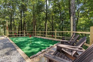 Ein Minigolfplatz mit Holzzaun, grüner Kunstrasen und Holzliegen.