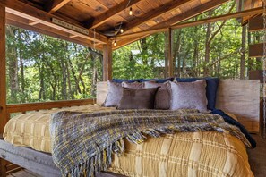 Une chambre dans une cabane en bois, avec un lit, des oreillers et une couverture.