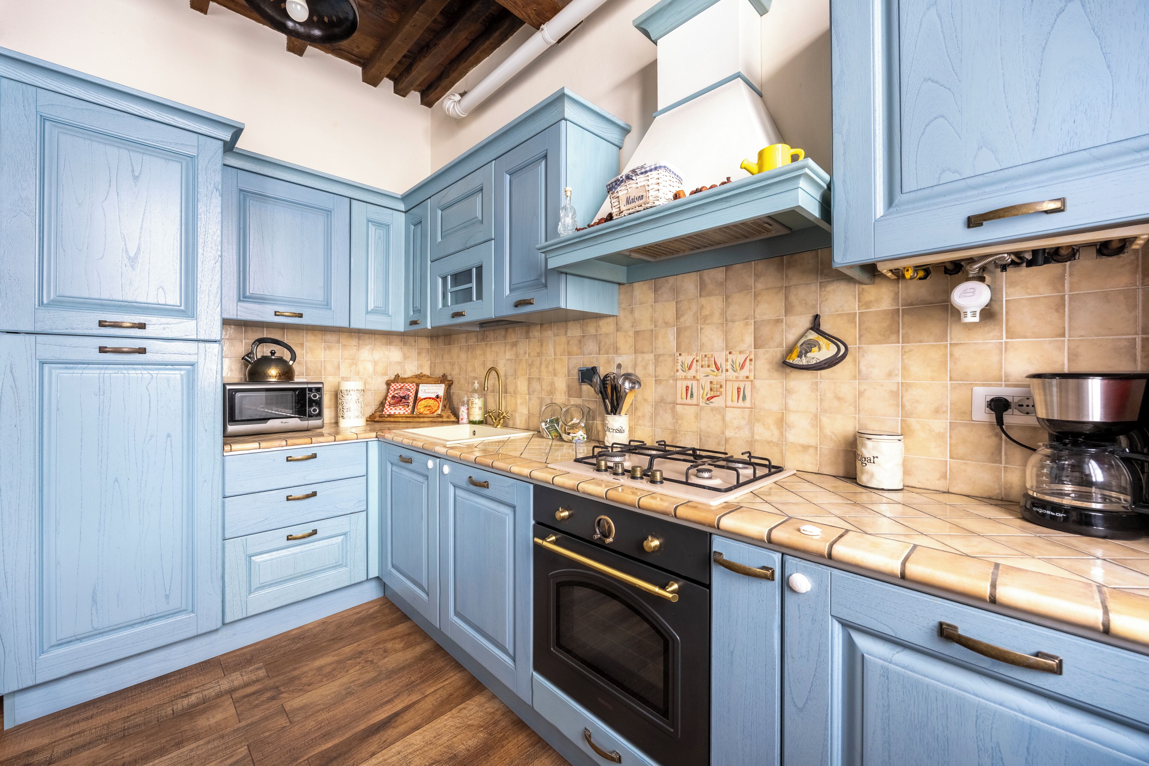 Une cuisine avec des meubles de couleur bleu clair, une cuisinière à gaz, un four à micro-ondes et une machine à café.