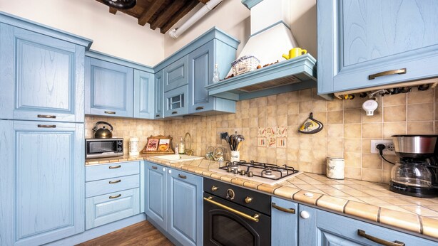 Une cuisine avec des meubles de couleur bleu clair, une cuisinière à gaz, un four à micro-ondes et une machine à café.
