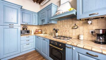 Une cuisine avec des meubles de couleur bleu clair, une cuisinière à gaz, un four à micro-ondes et une machine à café.
