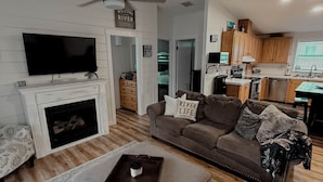 A living room with a fireplace, a television, a sofa, and a coffee table. - The Sunland Hideaway -Spacious 4-bedroom house in tranquil Sunland Estates. (Quincy)