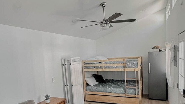 A room with a bunk bed, a sofa, a ceiling fan, a refrigerator, and a small table with a plant. - The Sunland Hideaway -Spacious 4-bedroom house in tranquil Sunland Estates. (Quincy)