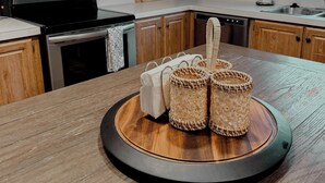 A kitchen with wooden cabinets, a stove, a dishwasher, and a round wooden table with woven baskets. - The Sunland Hideaway -Spacious 4-bedroom house in tranquil Sunland Estates. (Quincy)