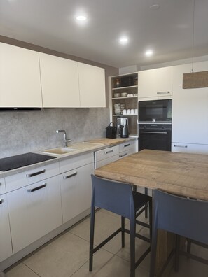 A modern kitchen with white cabinets, a stainless steel sink, a coffee maker, and a built-in oven. - Spacious 105 m² apartment at the base of the slopes in the village of Les Deux Alpes 1800 (Les Deux Alpes)