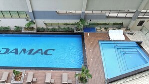 Un'ampia piscina interna con la scritta 'DAMAC' sull'acqua, circondata da sdraio e piante in vaso.