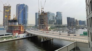 Panorama urbano con grattacieli, un ponte sull'acqua e un porto turistico con barche.