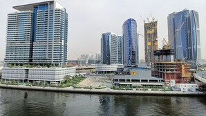Panorama moderno di una città con grattacieli, una banchina e gru edili.
