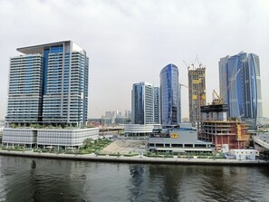 Eine moderne Skyline mit Hochhäusern, einer Uferpromenade und Baukränen.