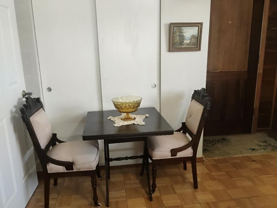 A dining area with a table and two chairs, a decorative bowl on the table, and a framed picture on the wall.