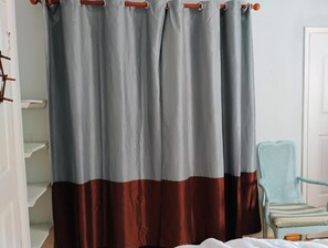 Ein Zimmer mit einem Bett, einem Sessel und einem Vorhang.