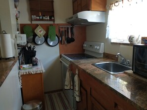 Una cocina compacta con estufa, lavamanos y microondas.
