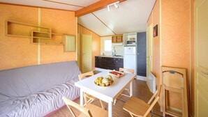 Quarto compacto com sofá, mesa de jantar com cadeiras, cozinha compacta e armário.