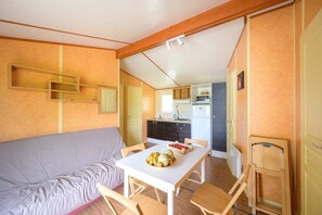Une pièce compacte comprenant un canapé, une table à manger avec des chaises, un coin cuisine et une armoire.