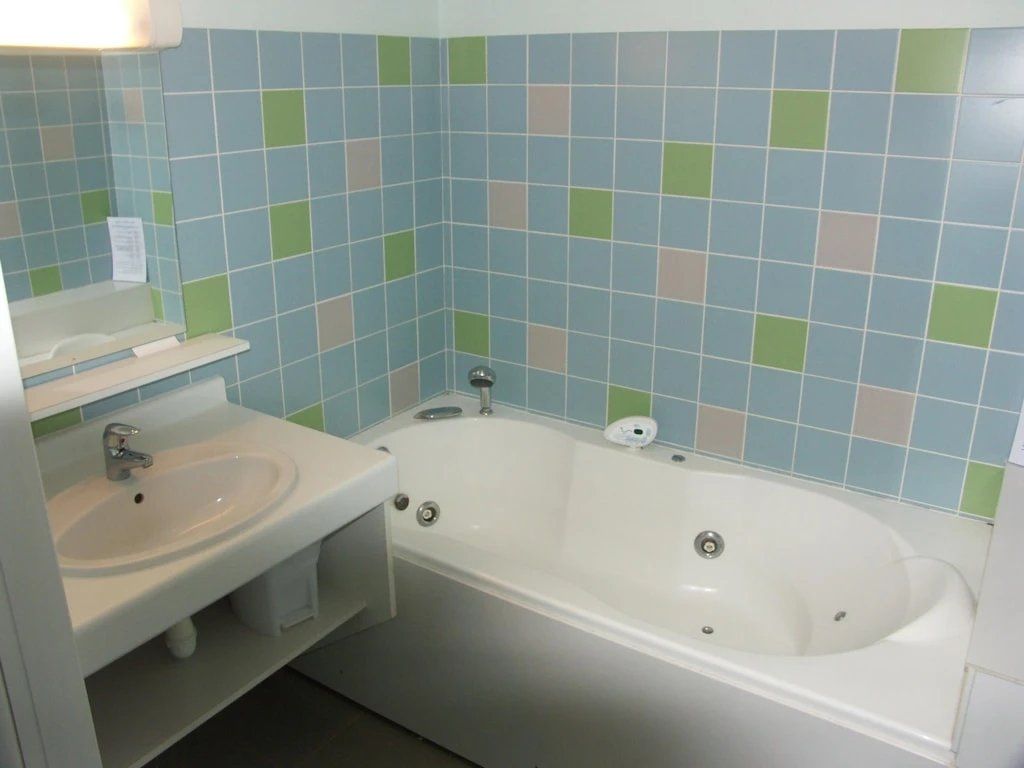 Een badkamer met een wit wastafel, een bad en een spiegel.