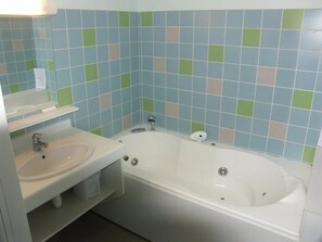A bathroom with a white sink, a bathtub, and a mirror.