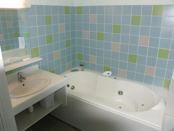 A bathroom with a white sink, a bathtub, and a mirror.